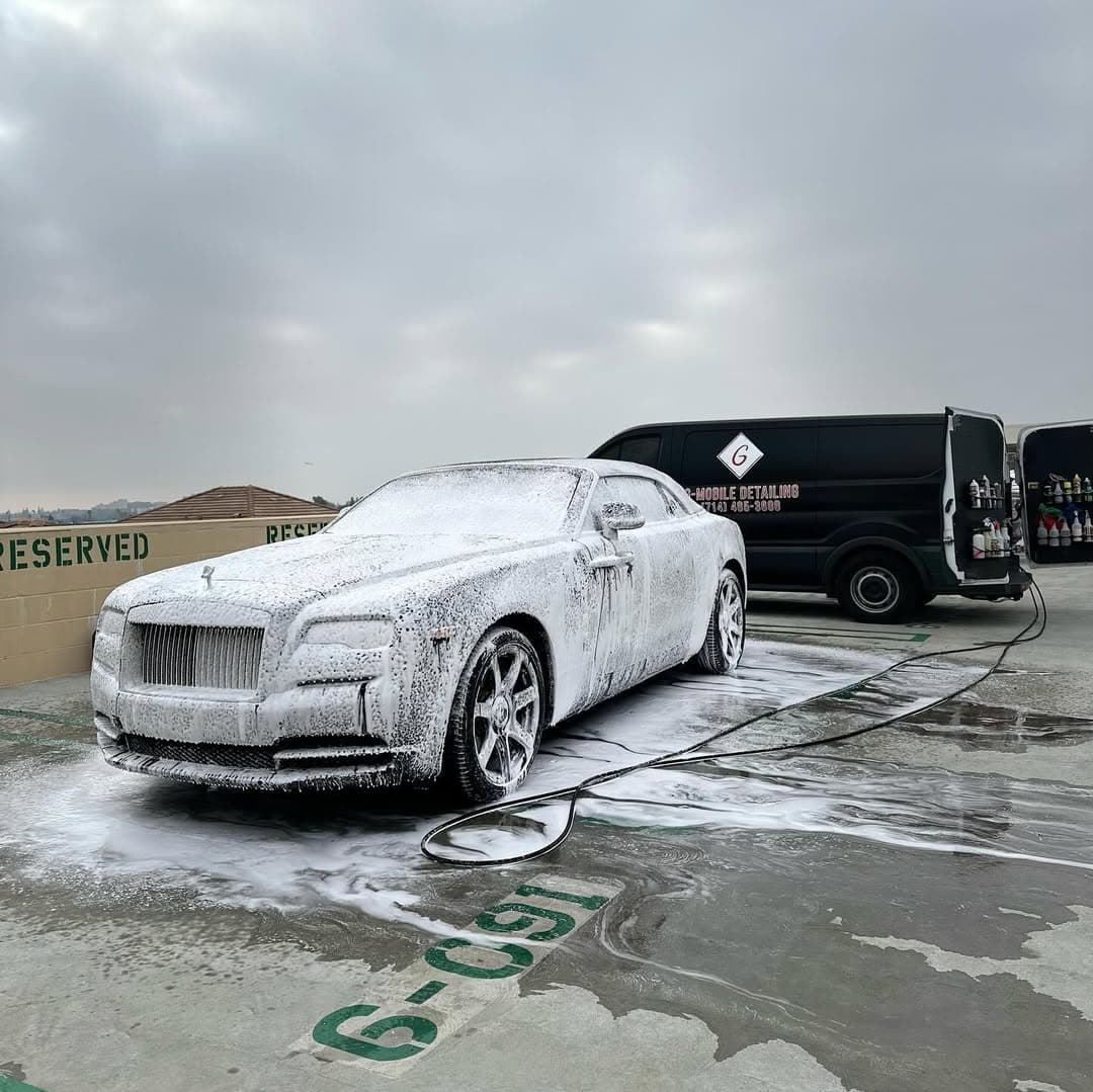 Rolls-Royce Dawn covered in thick foam during a hand wash, G Mobile Detailing van behind
